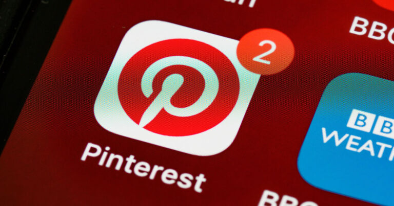 Gros plan sur l'écran d'un smartphone affichant l'icône de l'application Pinterest avec une pastille de notification rouge indiquant le chiffre 2.