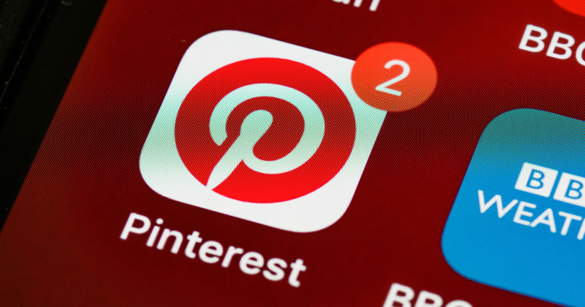 pinterest-en-2026-og-image Gros plan sur l'écran d'un smartphone affichant l'icône de l'application Pinterest avec une pastille de notification rouge indiquant le chiffre 2.